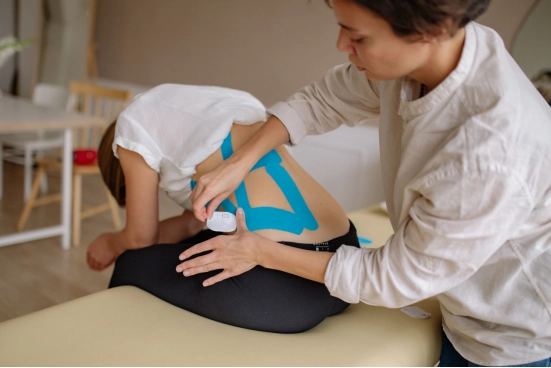 therapist-applying-blue-kinesiology-tape-to-patients-back